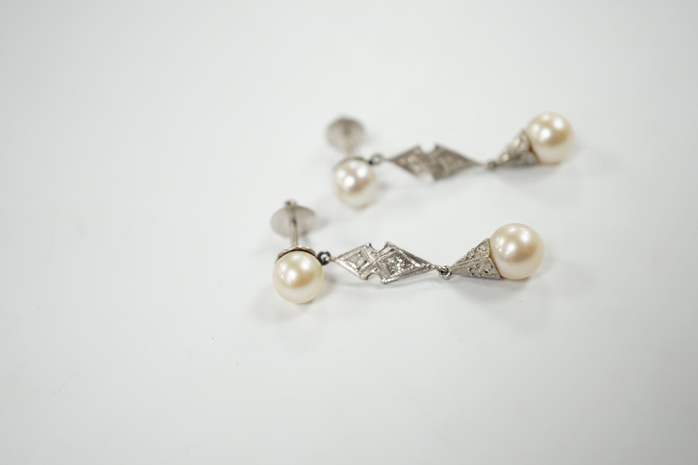 A pair of white metal, two stone cultured pearl and two stone diamond chip set drop earrings, 37mm, gross weight 6.1 grams.